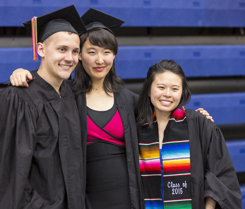Three graduates posing arm in arm